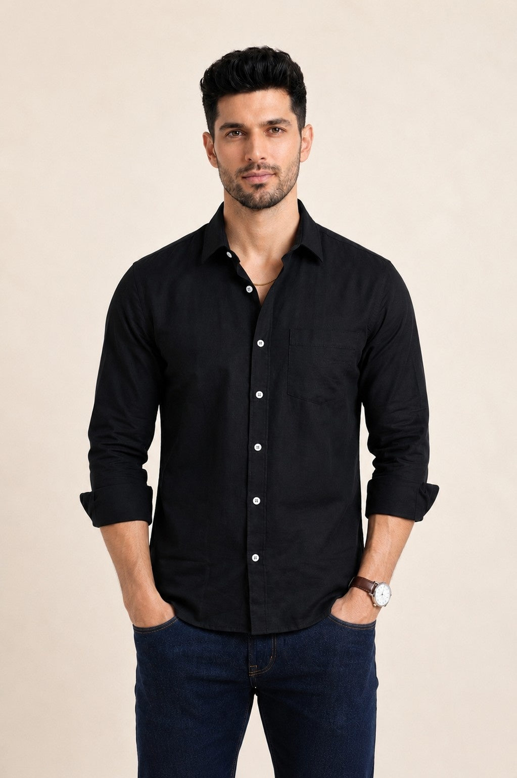 Man wearing a black shirt and dark pants against a beige background