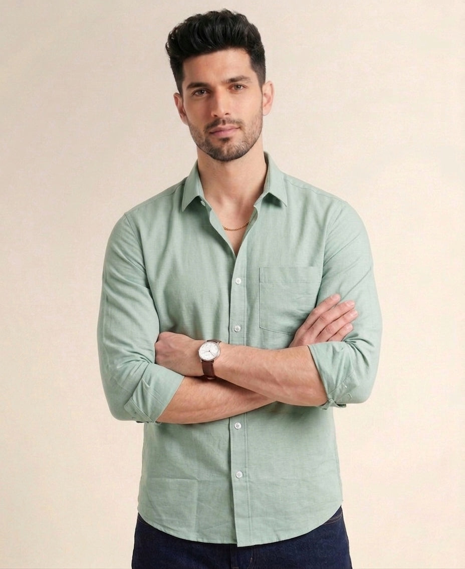 Man wearing a light green shirt with rolled-up sleeves against a beige background
