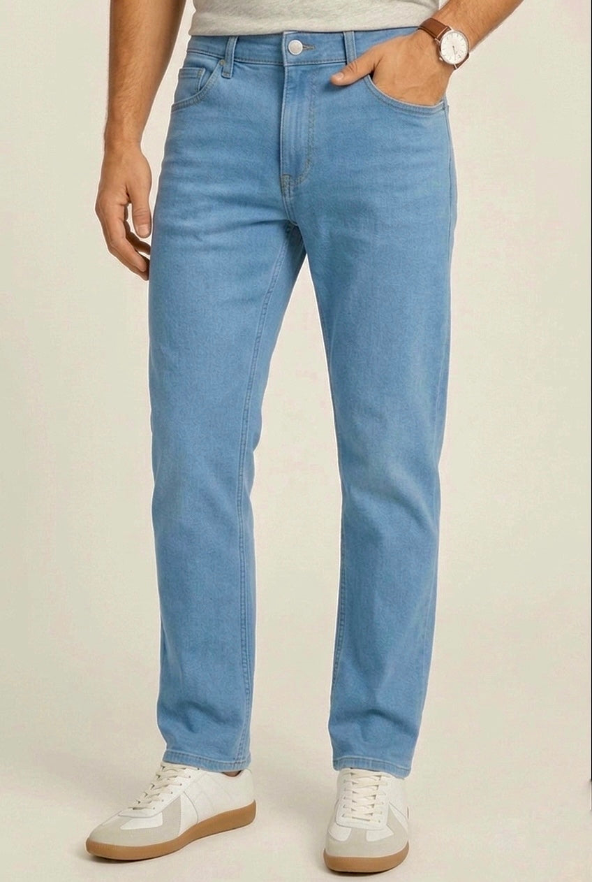 Person wearing light blue jeans and white sneakers on a plain background