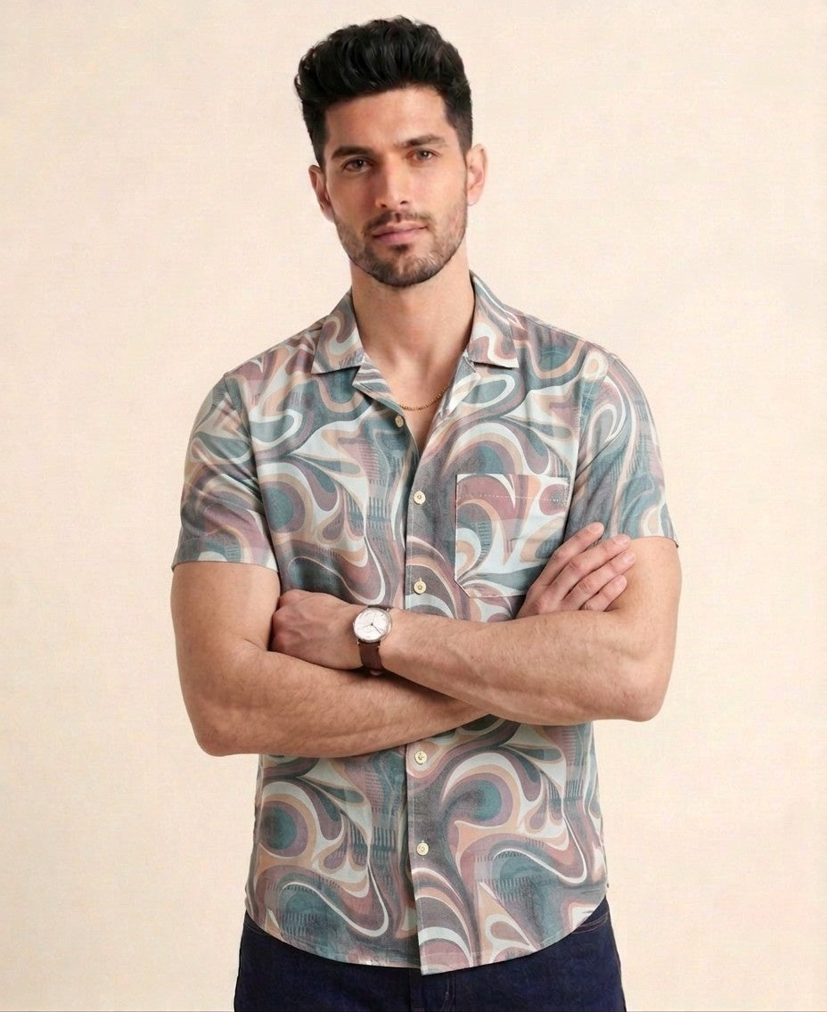 Man wearing a patterned shirt with his arms crossed on a beige background