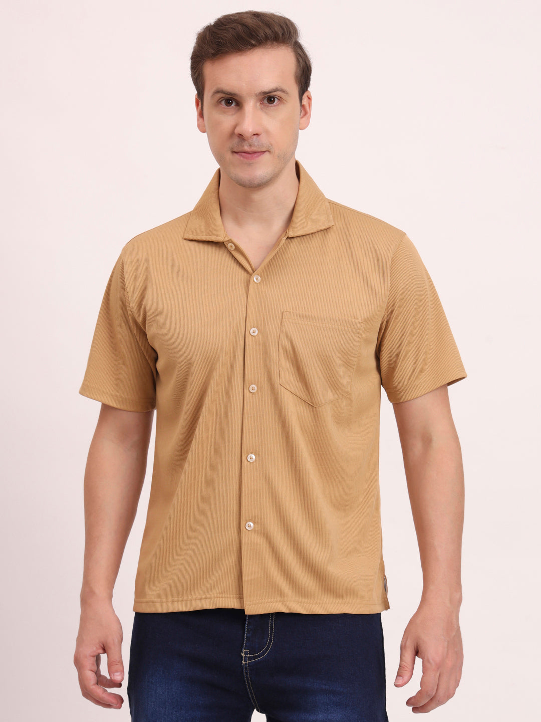 Man wearing a beige tan short-sleeve shirt with a collar on a light pink background