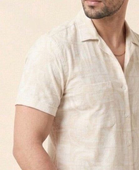 Man wearing a beige patterned shirt against a beige background